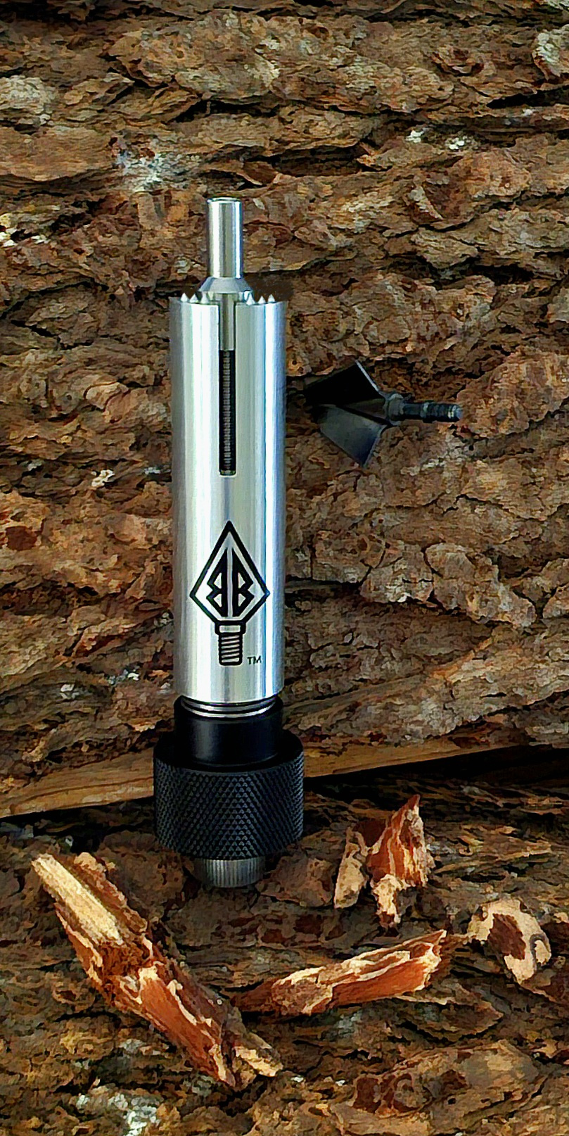 Broadhead Buddy removal tool beside a stuck broadhead in tree bark